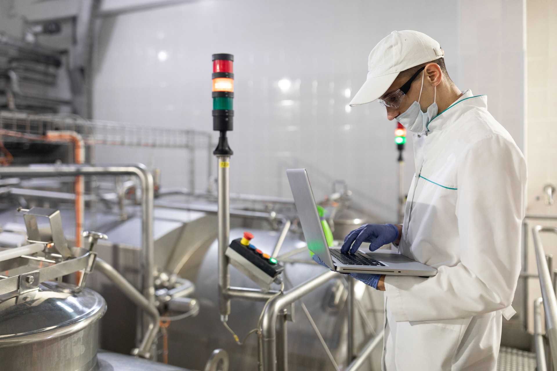 man in a white robe and a mask with a laptop in his hands is at the factory